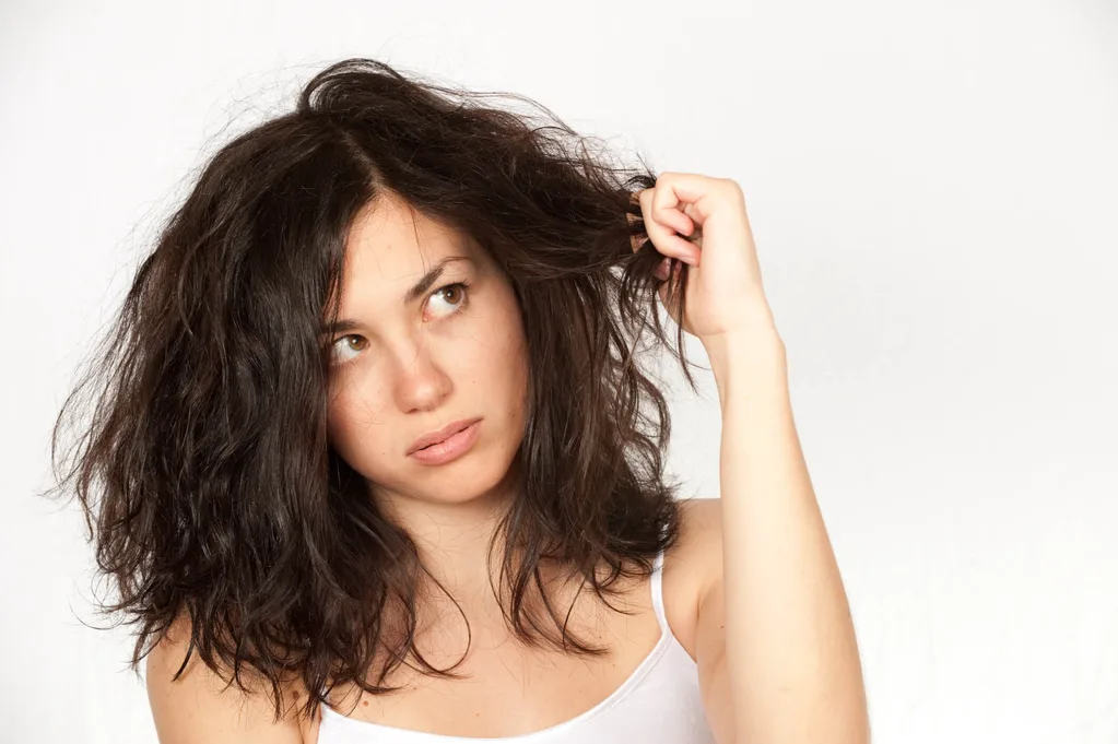 A woman holding her wavy hair against a white background