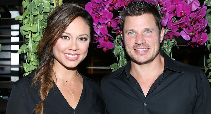 Couple smiling in front of vibrant pink flowers, both wearing black shirts, with greenery in the background.