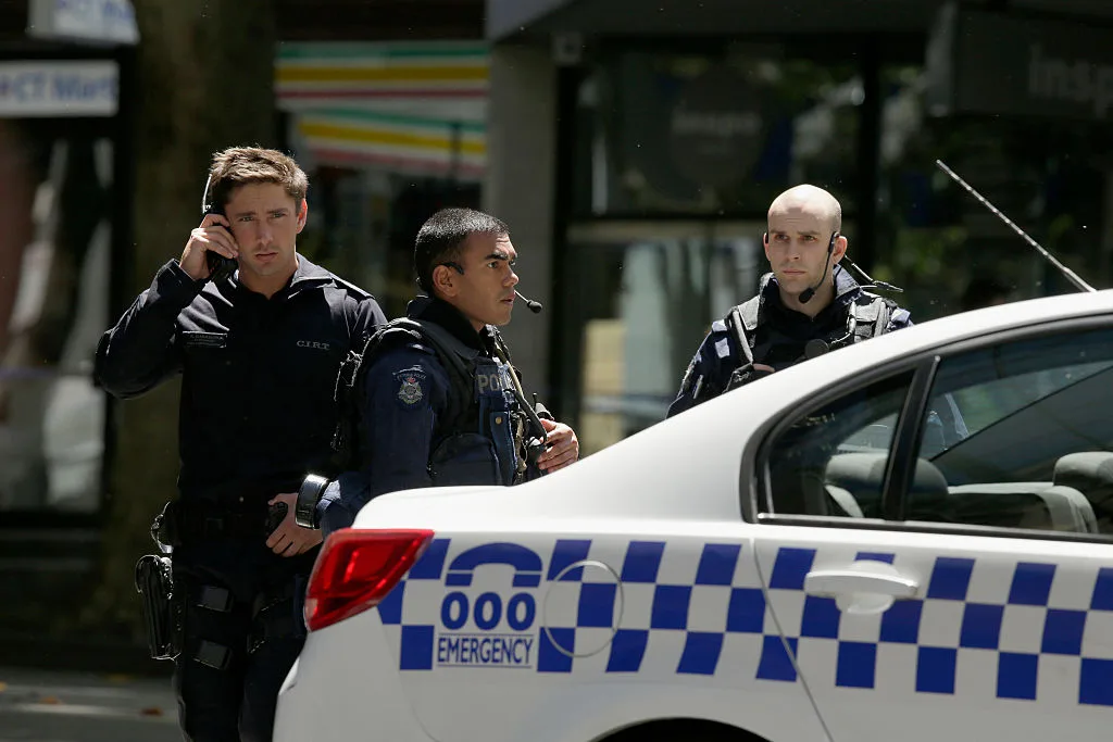Three Australian police next to a police car