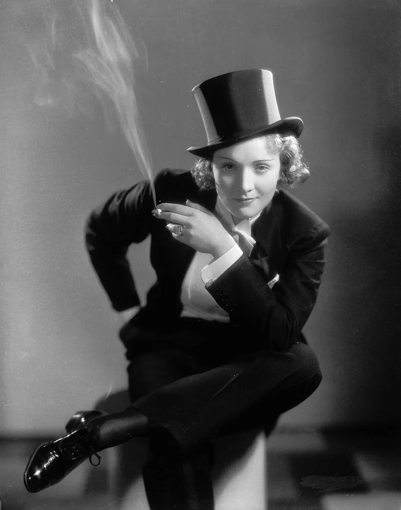 A black and white portrait of Marlene Dietrich in a suit and tophat