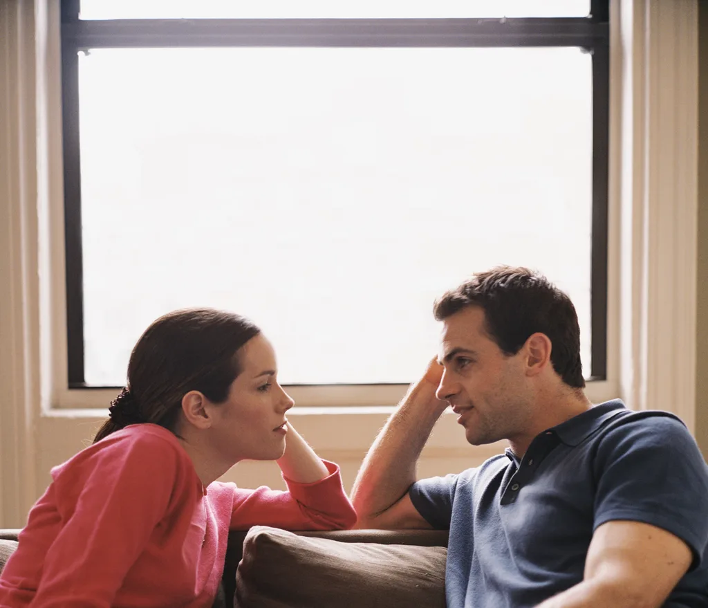 A girl and a guy looking at each other while sitting on a couch