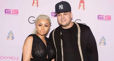 Two people posing together at an event, with branded backdrops featuring cartoon icons and logos.