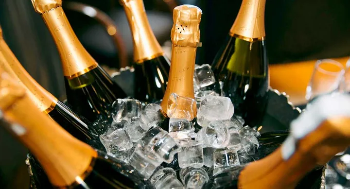 Bottles of champagne chilling in an ice bucket with gold foil caps.