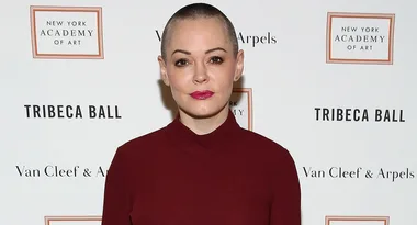A person with a shaved head wearing a dark red top at the Tribeca Ball, New York Academy of Art backdrop.