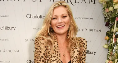 Person wearing leopard print jacket at a Charlotte Tilbury event with a flower backdrop, smiling.