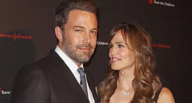 Couple posing on a red carpet at a Save the Children event, with black background and Johnson & Johnson logos.
