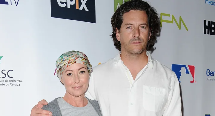 Two people posing at an event, one wearing a floral headscarf, in front of a backdrop with logos like epix and HBO.