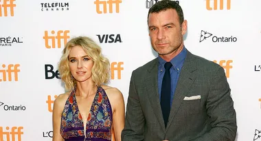 "Two people posing on the TIFF red carpet; backdrop shows festival logos and sponsor names."