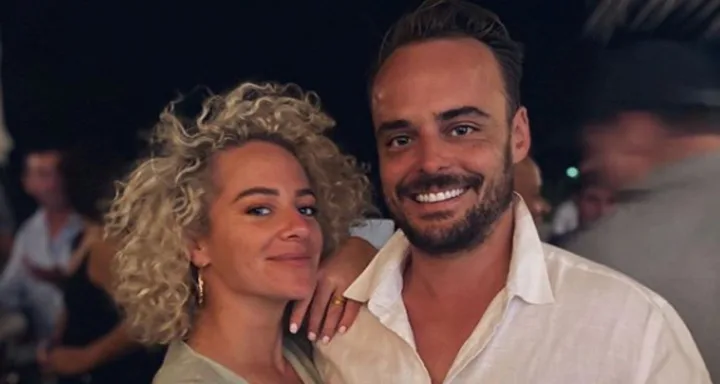 A smiling couple poses closely together at an outdoor evening event.