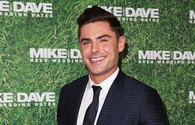 Man in suit smiling at "Mike and Dave Need Wedding Dates" event.