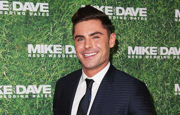 Man in suit smiling at "Mike and Dave Need Wedding Dates" event.