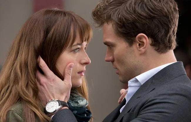 A man in a suit gently holds a woman&rsquo;s face in an emotional close-up, both looking into each other's eyes.