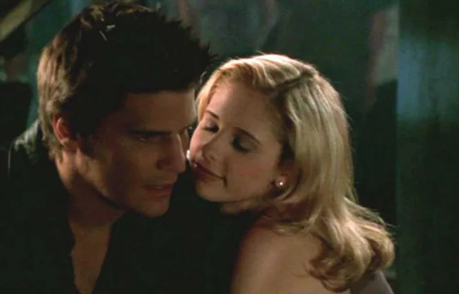 Intimate moment between a man and woman embracing in a dimly lit setting.
