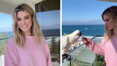 Delta Goodrem feeds friendly cockatoo a biscuit on her balcony