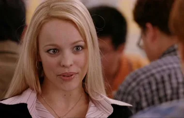 A blonde woman in a striped shirt speaks, set in a casual indoor setting.