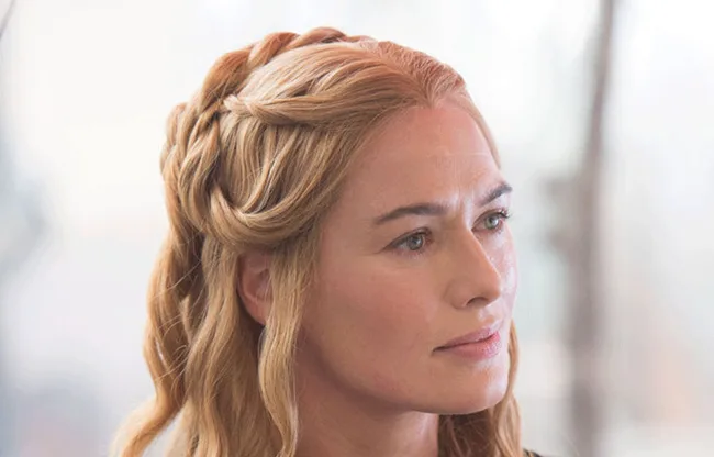 A woman with braided blonde hair looks to the side, set against a blurred light background.