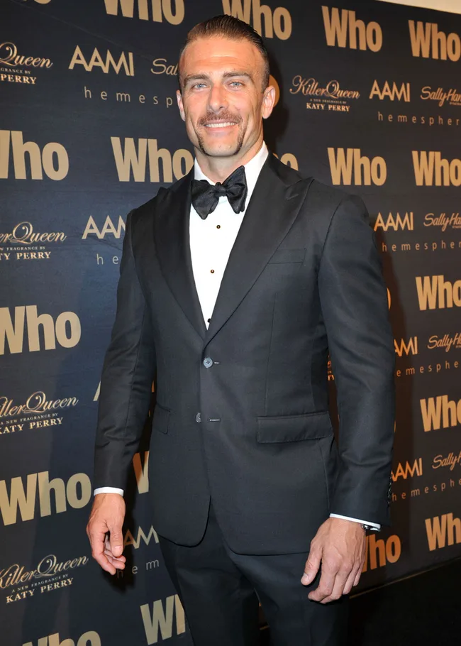 Man in a tuxedo with bow tie on the "Who" event backdrop.