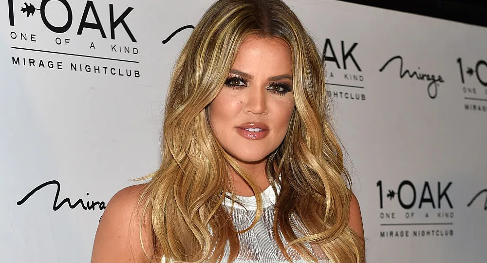 Woman with long blonde hair at a nightclub event, standing in front of a backdrop with the logo "1 OAK Mirage Nightclub".