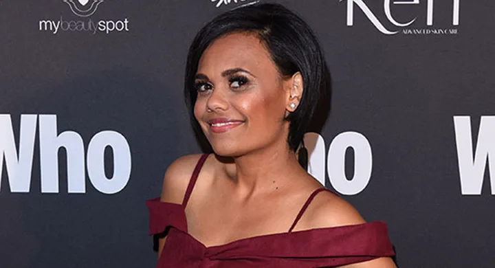 Woman in burgundy dress posing on red carpet with "Who" magazine backdrop.