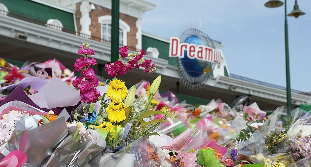 Floral tributes outside Dreamworld's entrance, with colorful flowers wrapped in paper.