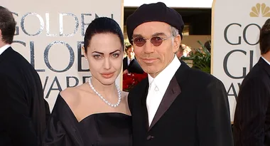 Two people pose together at the Golden Globe Awards, wearing formal attire.