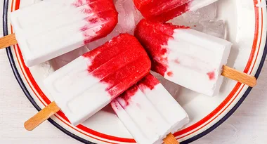 Red and white popsicles in a bowl with ice cubes.