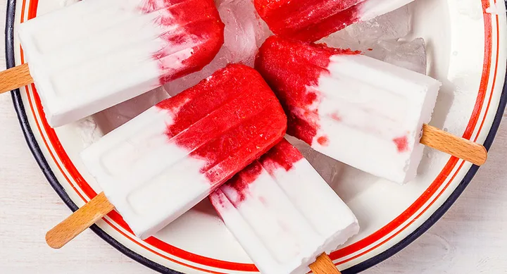 Red and white popsicles in a bowl with ice cubes.