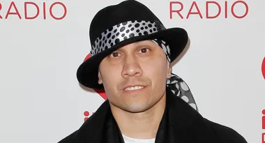 Man in a black hat with polka-dotted bandana at a radio event backdrop.