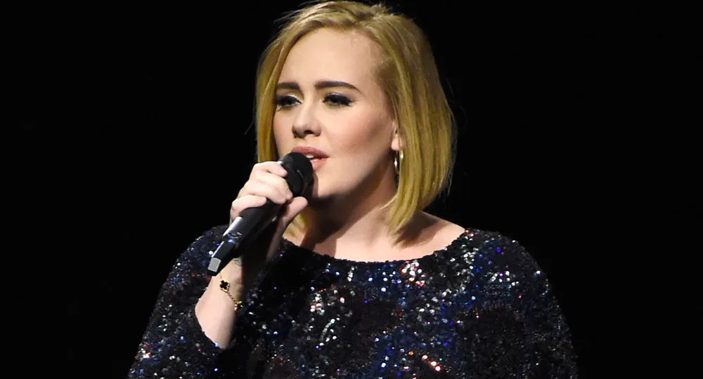 Singer in a sparkly dress holding a microphone during a performance.