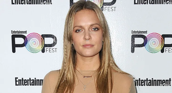 Woman with long hair at Entertainment's PopFest event, standing against a logo backdrop.