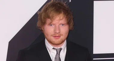 Young man with red hair in a black suit and tie at a formal event.