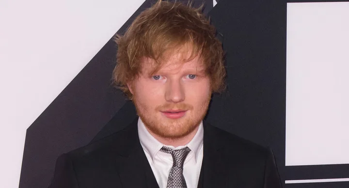 Young man with red hair in a black suit and tie at a formal event.