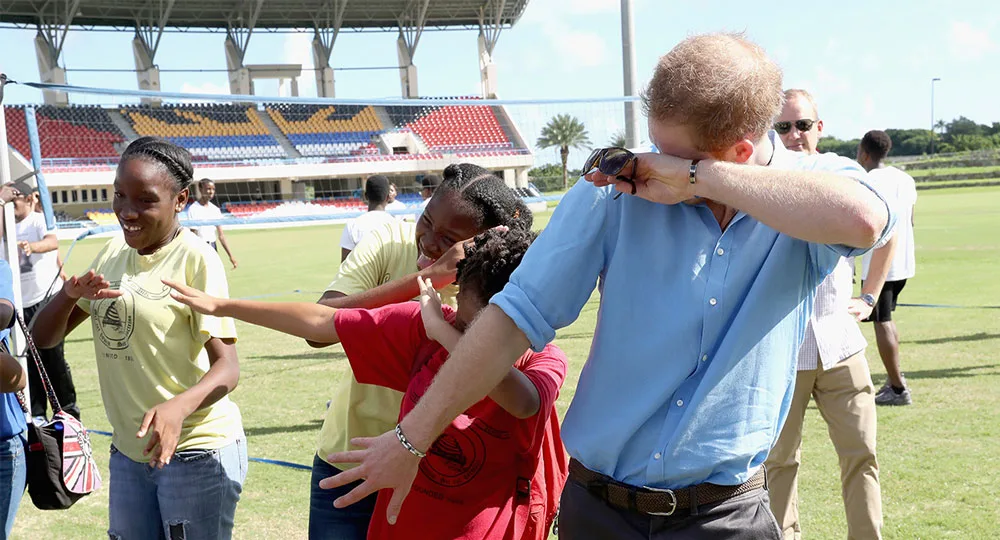 Prince Harry does the 'dab' as he meets school girls as he attends a youth sports festival at Sir Vivian Richards Stadium showcasing Antigua and Barbuda's national sports, on the second day of an official visit to the Caribbean on November 21, 2016 in Antigua, Antigua and Barbuda.
