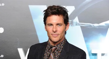 Man in a patterned suit with a tie poses in front of a "Westworld" backdrop.