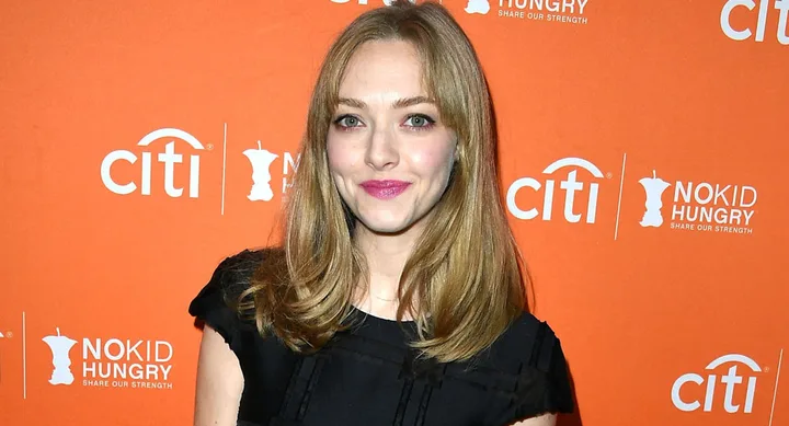 ```plaintext
Person smiling at event, "No Kid Hungry" logos on orange backdrop.
```