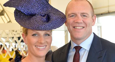 Two people posing together; the woman is wearing a purple hat, and both are smiling.