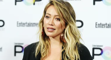 ```plaintext
A person with long blonde hair at an Entertainment Weekly event, wearing large hoop earrings.
```