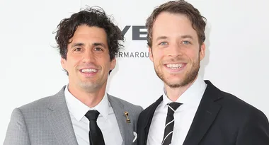 Two smiling men in suits, posing together against a light background at a formal event.