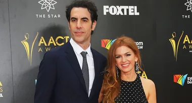 Two people in formal attire at the AACTA Awards, smiling, with logos and event signage in the background.
