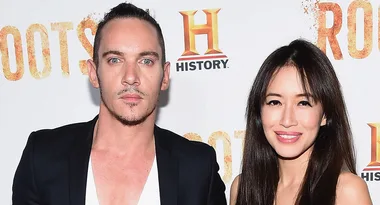 Two individuals smiling at a "Roots" History Channel event, standing in front of a promotional backdrop.