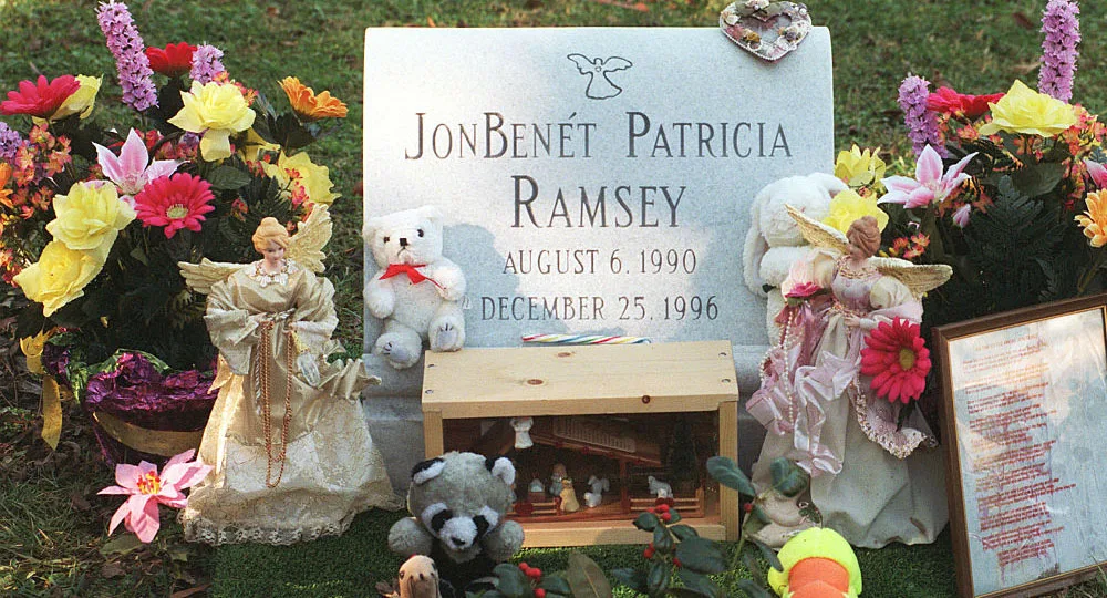 Grave of JonBenét Ramsey surrounded by flowers, dolls, and toys.