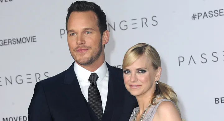 A suited man and a woman in a dress pose together at a "Passengers" event backdrop.
