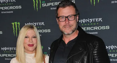 Two individuals posing at a Monster Energy Supercross event with branding in the background.