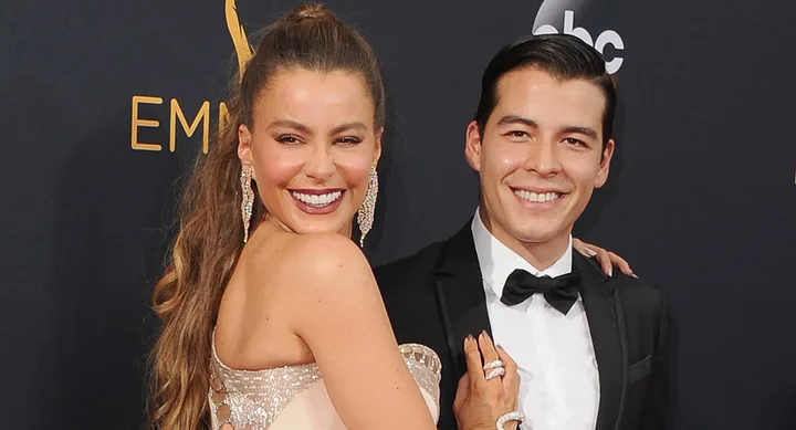 A woman and man in formal attire smiling at a red carpet event.
