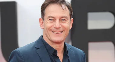 Man in blue shirt, smiling at an event, with a blurred background.