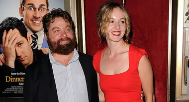 Two people smiling at a movie premiere with a poster for "Dinner for Schmucks" in the background.