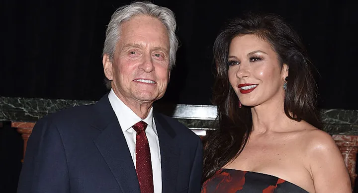 A man in a suit and a woman in a strapless dress pose together at an event.