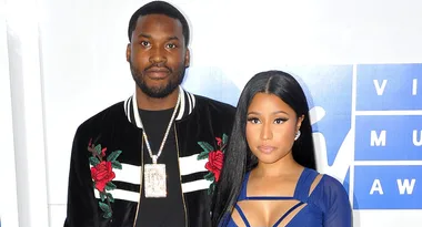 Two people posing for a photo at a formal event, one wearing a floral jacket and the other a blue dress.