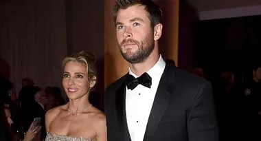 A man in a tuxedo and a woman in a strapless dress are attending a formal event.
