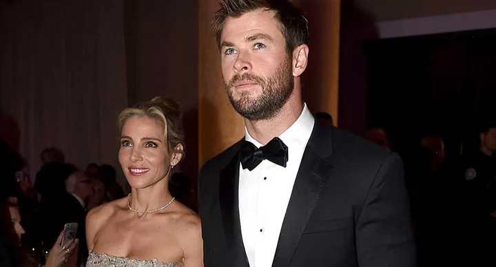 A man in a tuxedo and a woman in a strapless dress are attending a formal event.